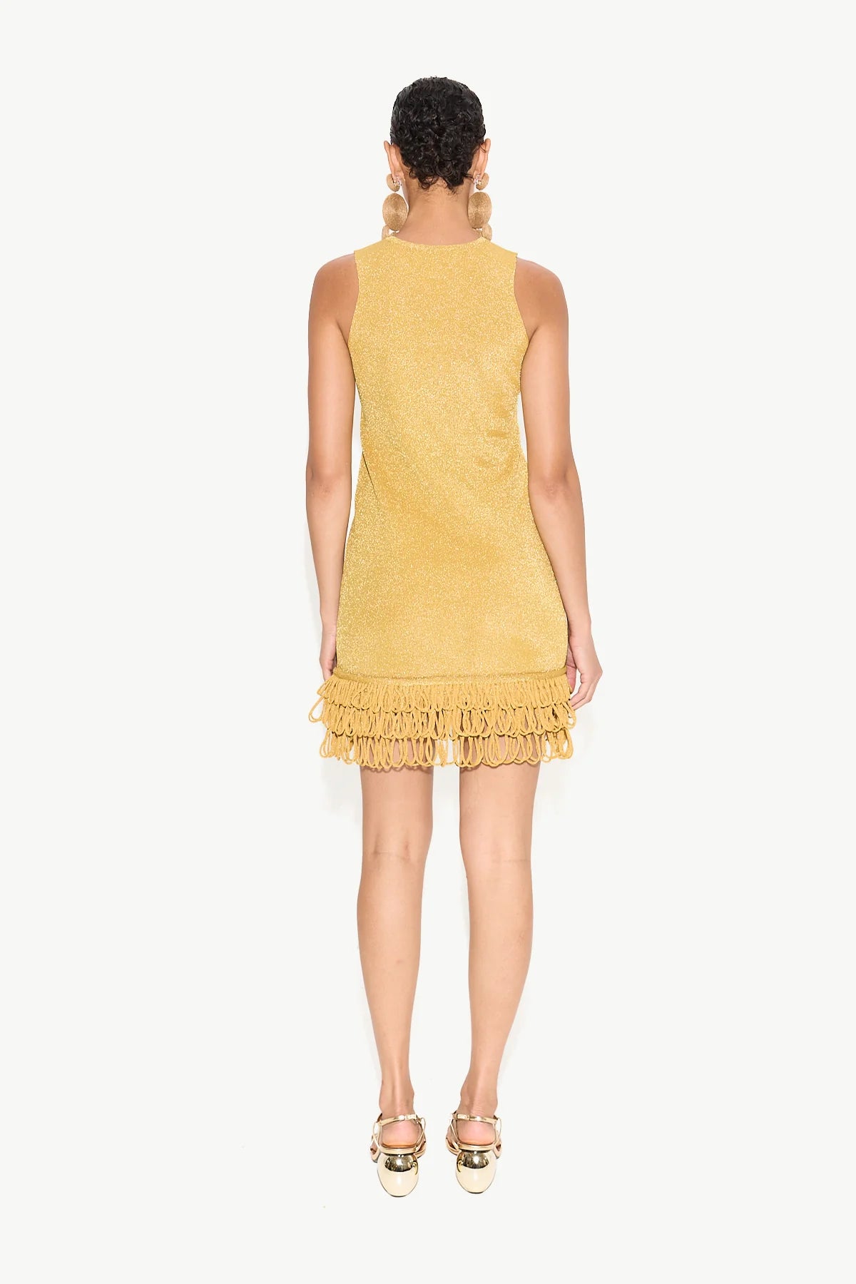 Woman wearing a yellow dress with ruffled hem on a white background