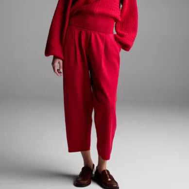 Person wearing a red outfit with a sweater and pants on a plain background