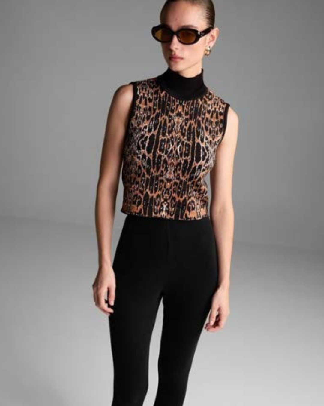 Person wearing a leopard print top and black pants on a gray background